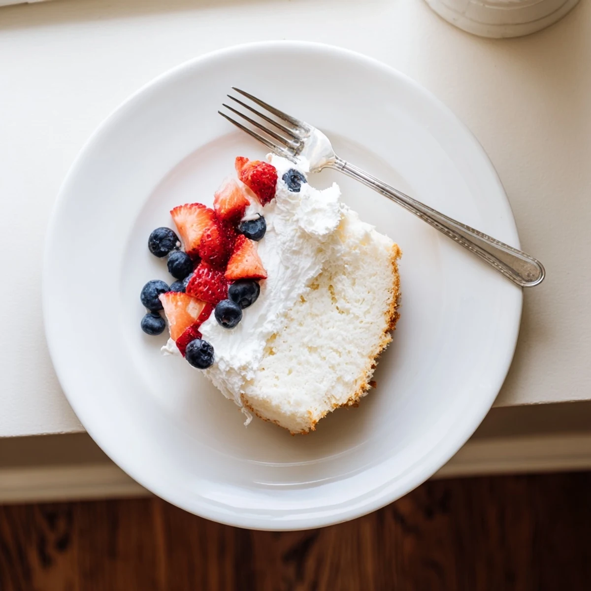 Freshly baked angel food cake rests on a wire rack, showcasing its fluffy, white texture and golden top, ready to be served.