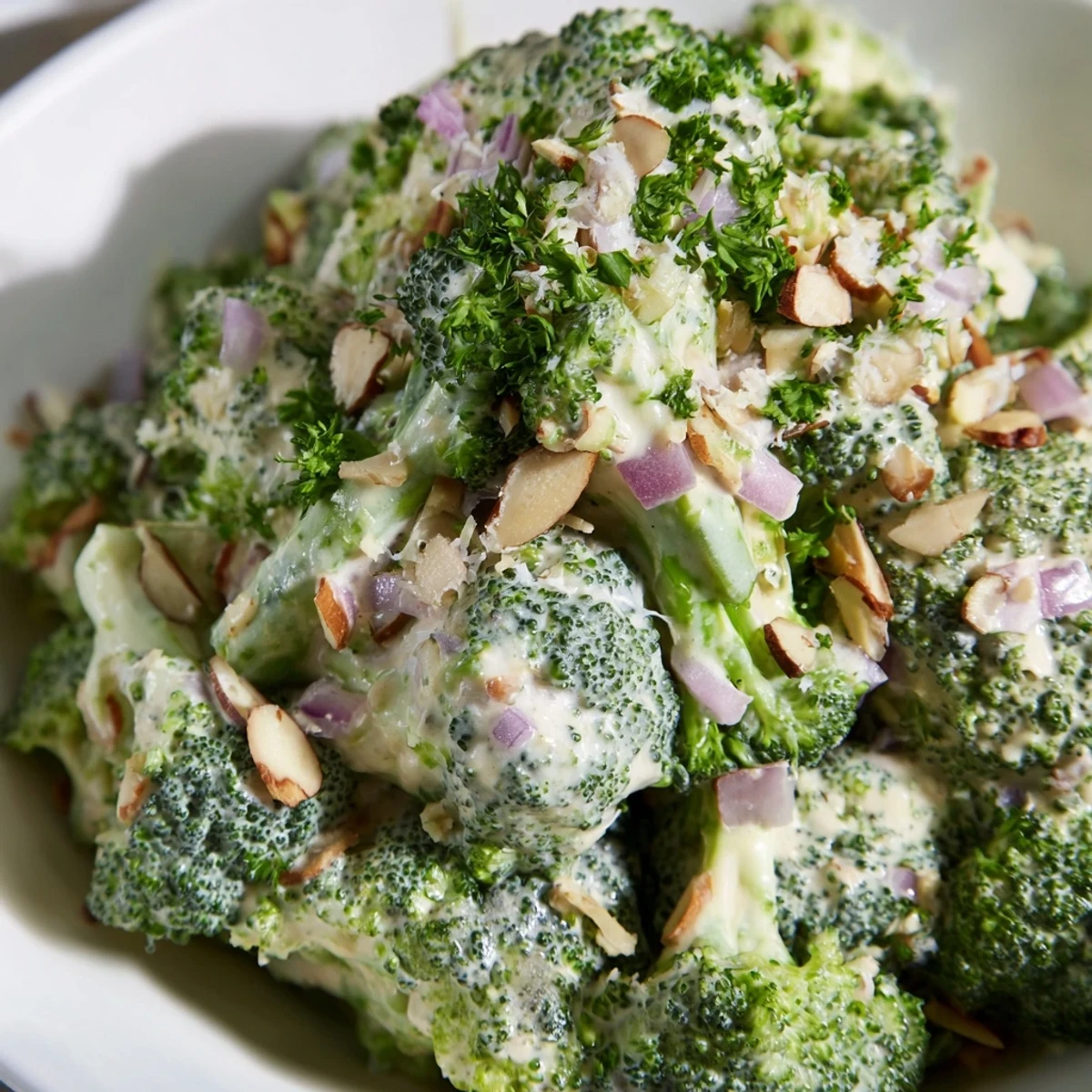 Bright green blanched broccoli florets tossed in a creamy garlic Parmesan dressing, garnished with toasted almonds and fresh parsley.