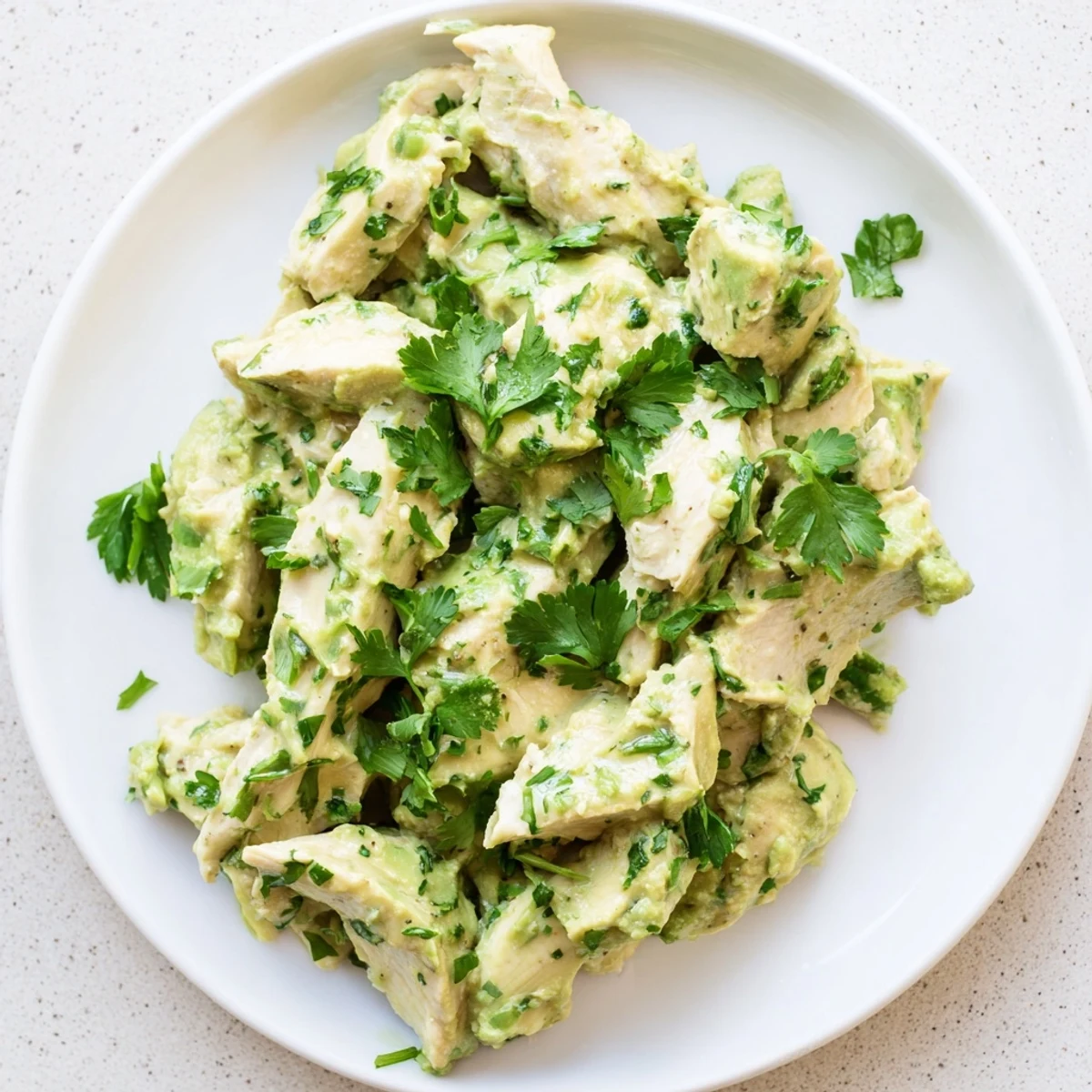 A vibrant bowl of avocado chicken salad with red onion, cucumber, and cilantro, ready for a light and easy meal.