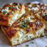 Homemade Fluffy Cottage Cheese Flatbread is topped with creamy dip and fresh herbs on a plate.