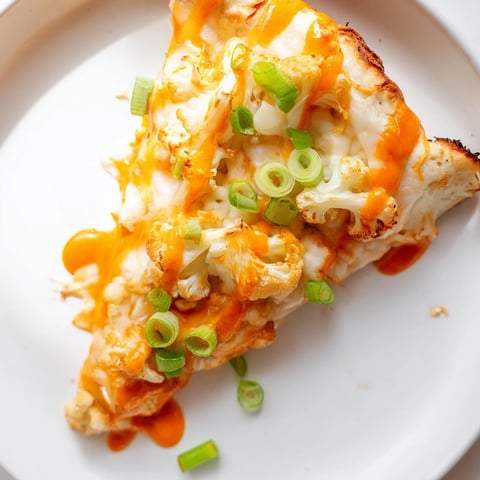 A golden, crispy Buffalo Cauliflower Pizza topped with melted mozzarella, spicy sauce, and fresh green onions.  