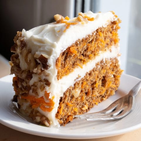 Freshly baked carrot cake layers stacked high, frosted with rich cream cheese icing and walnut pieces.