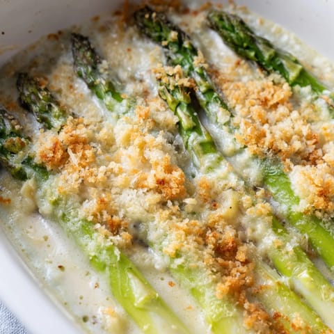 Asparagus Casserole featuring tender green spears in a creamy sauce, served in a white baking dish.
