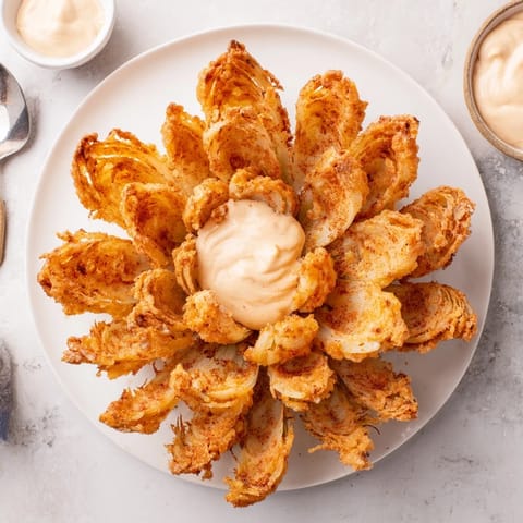 A homemade Blooming Onion recipe with seasoned batter, fried crisp, and paired with tangy dipping sauce.