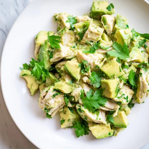 Fresh avocado chicken salad served in crisp lettuce cups, garnished with herbs and a lime wedge for a bright, healthy lunch.