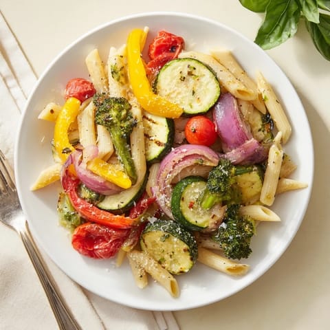 Freshly grated Parmesan crowns a serving of Pasta Primavera, garnished with basil and lemon wedges on a rustic wooden table.