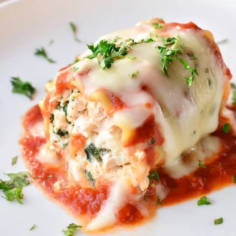 Freshly baked Chicken and Spinach Lasagna Rolls, garnished with parsley and served hot alongside a crisp green salad.