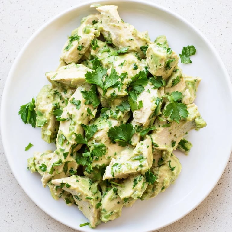 A vibrant bowl of avocado chicken salad with red onion, cucumber, and cilantro, ready for a light and easy meal.