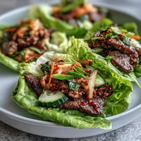 Bright Korean BBQ beef lettuce wraps piled high with kimchi, ready to assemble.